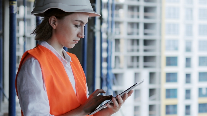 Arquitecta en una obra de construcción, analizando el proyecto con preocupación
